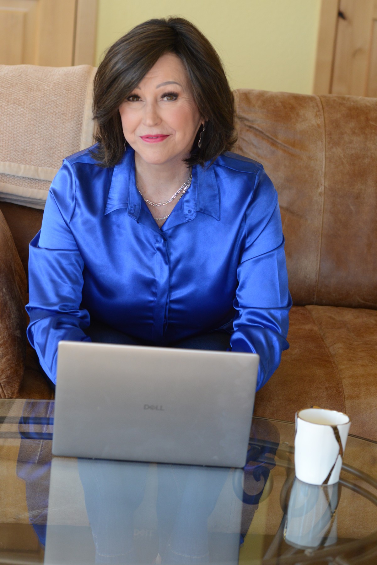 Jean Hendry in a blue blouse seated with a laptop